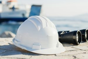 Casque d'ingénieur blanc et jumelles dans un port naval.